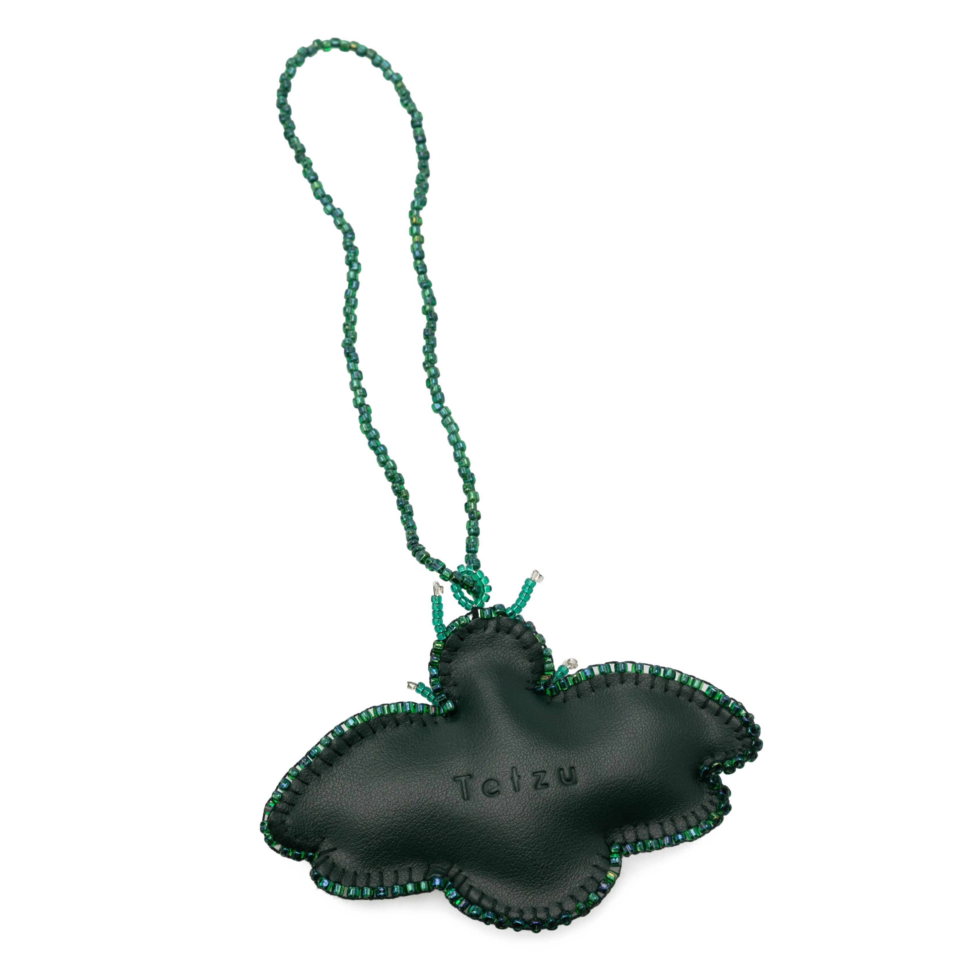 Green bag charm made from high-quality leather, featuring plastic bead embellishments and a signature logo on the back. Handcrafted in Portugal, this 6.5 cm x 9 cm keychain adds a sophisticated touch to any bag or keys.