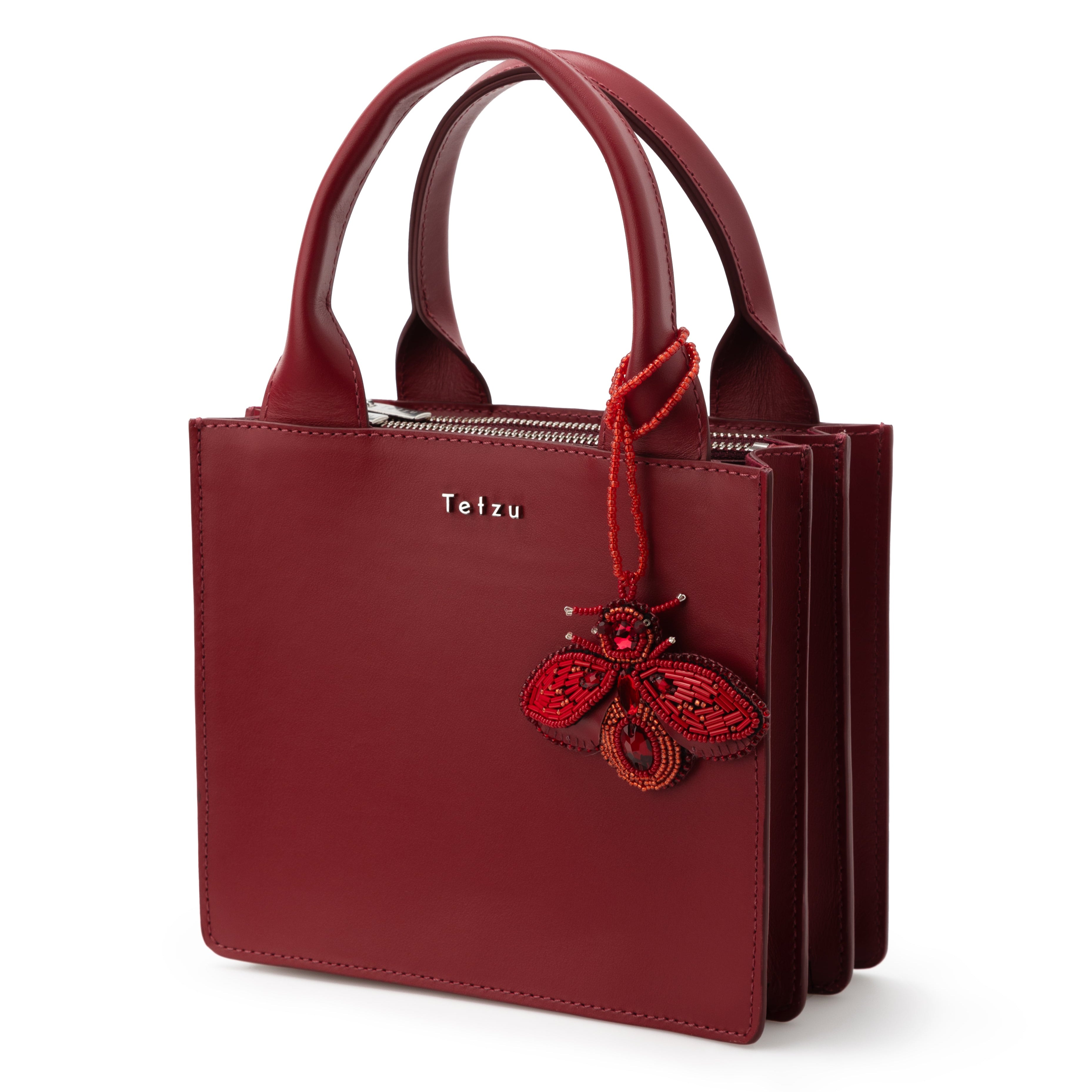 Cherry Red bag charm made from high-quality leather, featuring plastic bead embellishments and a signature logo on the back. Handcrafted in Portugal, this 6.5 cm x 9 cm keychain adds a sophisticated touch to any bag or keys.